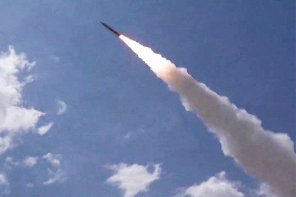 A missile is launched towards the sky, leaving a trail of white smoke.
