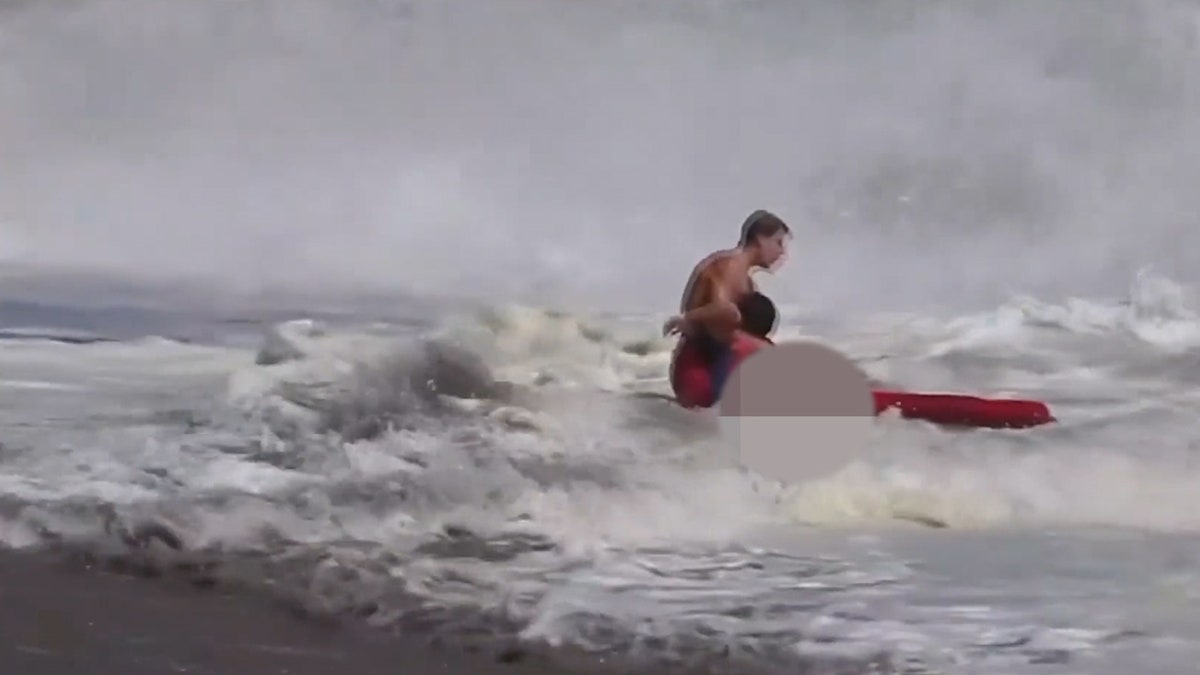 lifeguard holding kid, pulling child out of waves