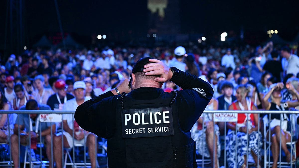 Secret Service member stands as audience waits for President Trump on National Mall.