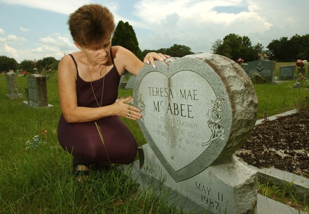 Dorothy McAbee touches the gravestone of her daughter, Teresa Mae McAbee, at the Center Hill Cemetery on Thursday, July 10, 2003. Teresa was 11 years old when she was murdered in 1987. (Stephen M. Dowell/Orlando Sentinel)