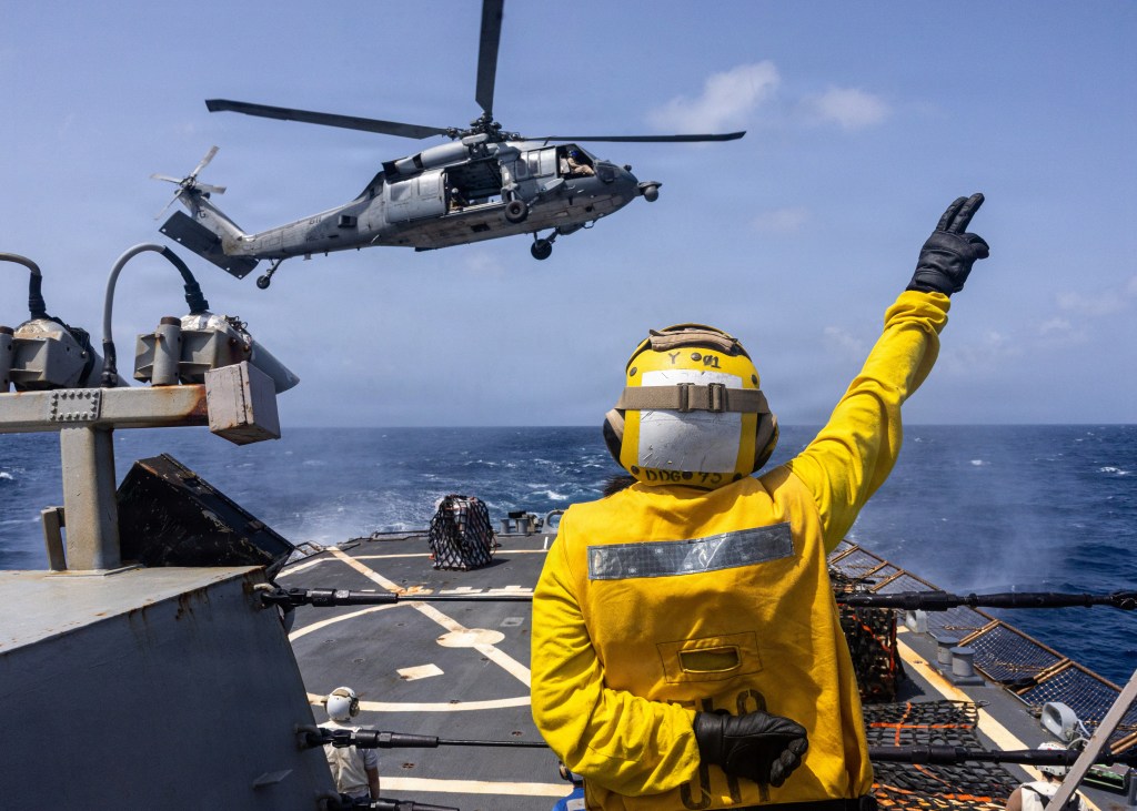 A U.S. Sailor signals to a MH-60S Sea Hawk helicopter attached to Helicopter Sea Combat Squadron (HSC) 5 from the flight deck of the Arleigh Burke-class guided-missile destroyer USS Donald Cook (DDG 75) in the Arabian Sea, June 17, 2026. Donald Cook is deployed to the U.S. 5th Fleet area of operations to support maritime security and stability in the Middle East. (U.S. Navy Photo)
