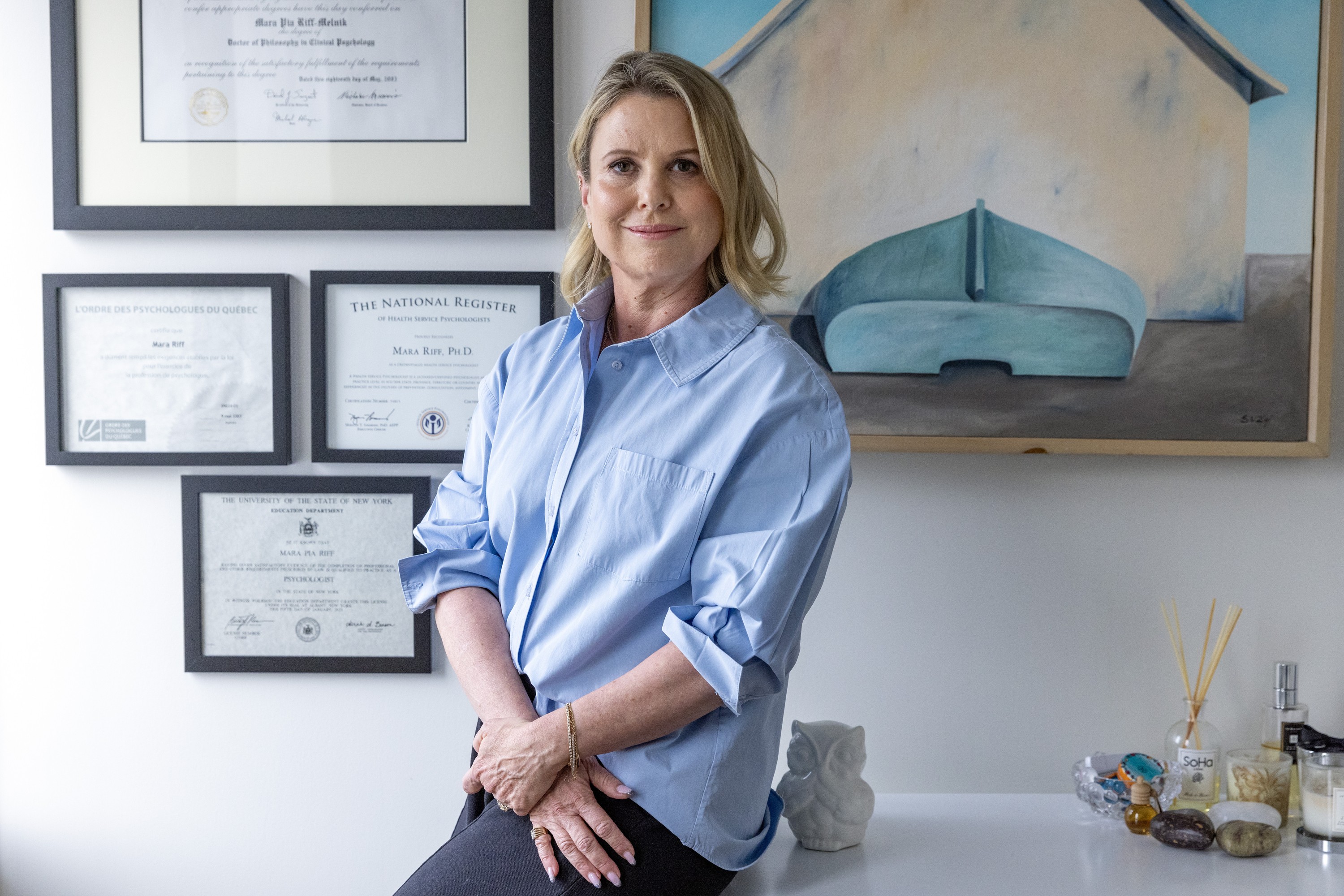 A woman poses in an office, with diplomas on the wall