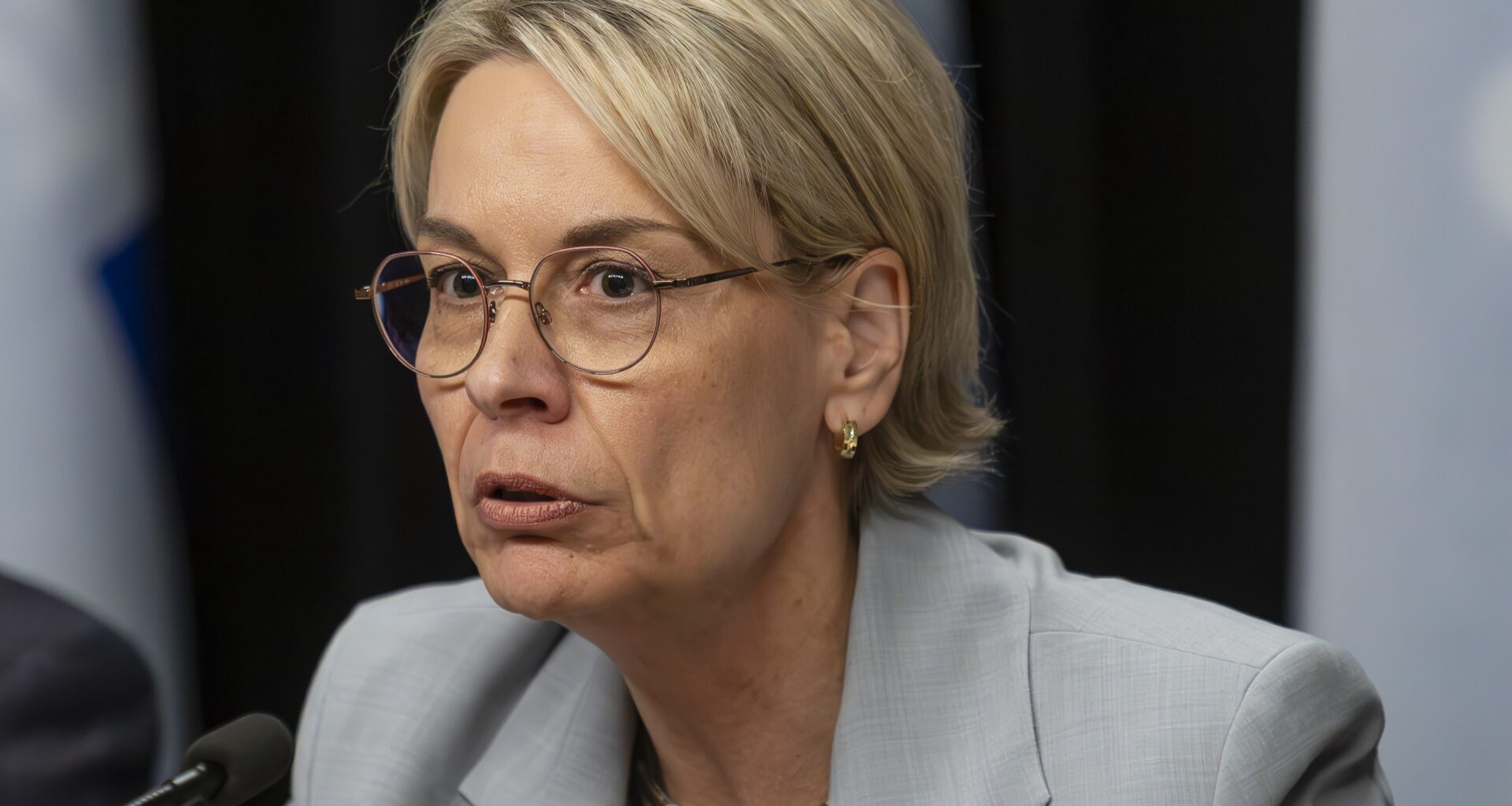 Woman sits at table speaking into microphone.