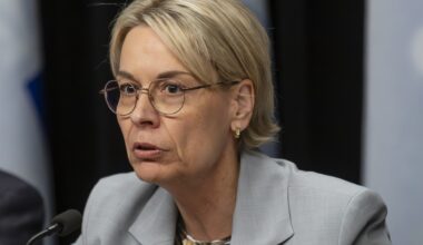 Woman sits at table speaking into microphone.