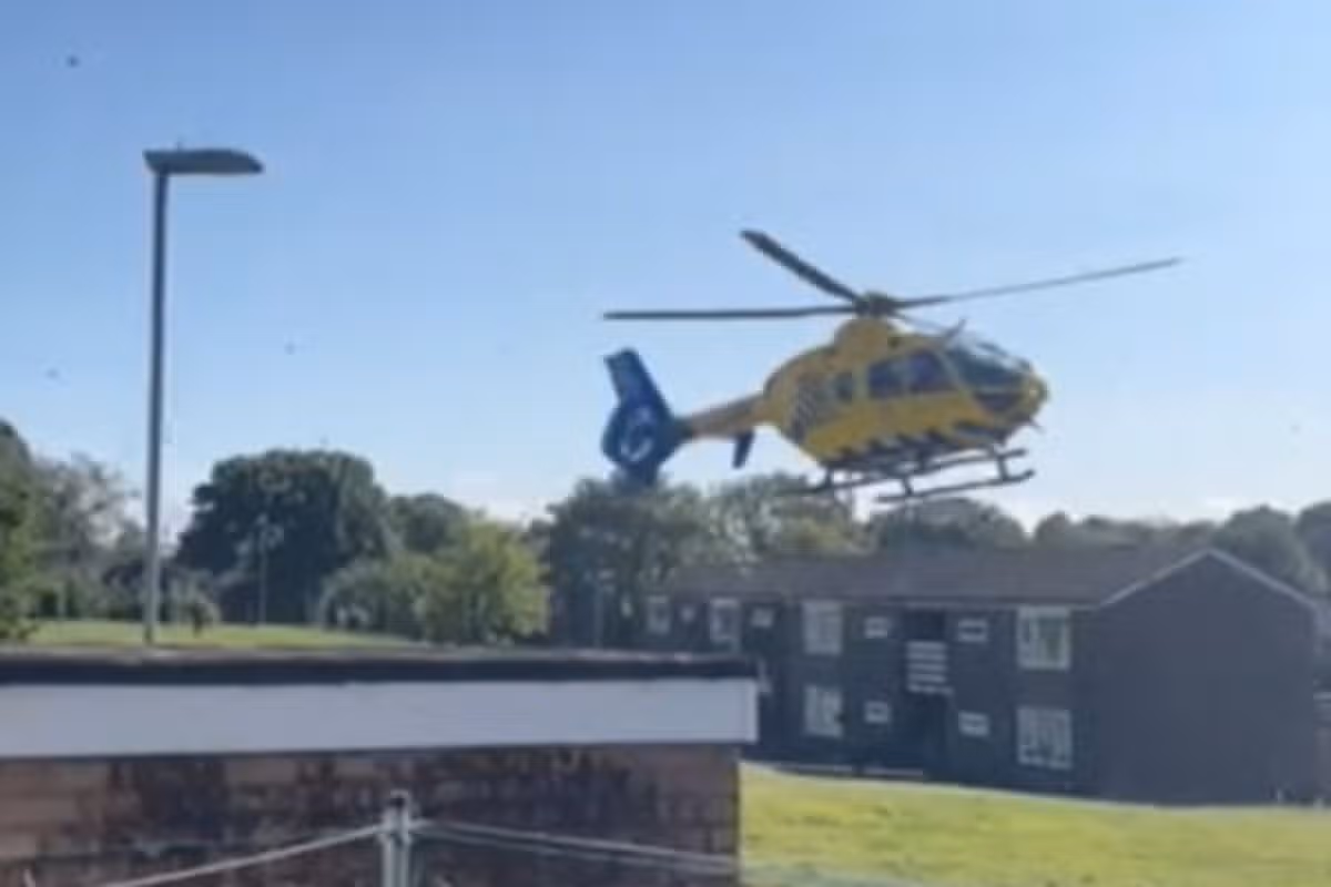 The air ambulance helicopter hovering just above a grassed area near Spotland Tops in Rochdale