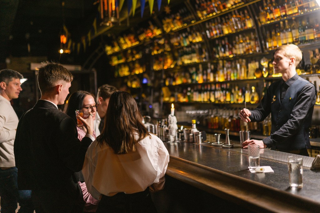 A bartender mixing drinks for customers at a bar.