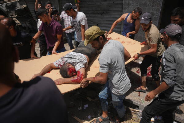 EDS NOTE: GRAPHIC CONTENT - Palestinians evacuate an injured man following an Israeli military strike, in Deir al-Balah, central Gaza Strip, Saturday, July 25, 2026. (AP Photo/Abdel Kareem Hana)