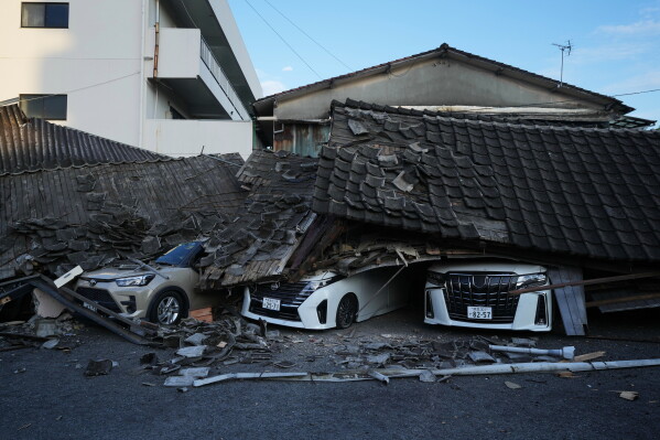 Vehicles are crushed under collapsed buildings in Yatsushiro, southwestern Japan, Wednesday, July 29, 2026, the day after an earthquake hit the area. (AP Photo/Hiro Komae)