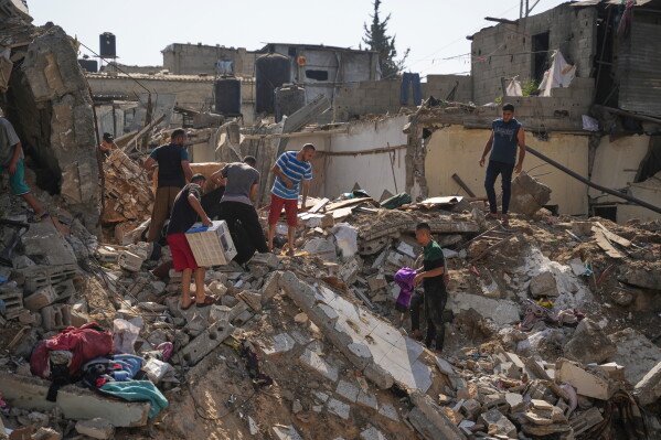 Palestinians save belongings from destroyed buildings at the scene of an Israeli airstrike at al-Maghazi refugee camp in the central Gaza Strip, Saturday, Aug. 1, 2026. (AP Photo/Abdel Kareem Hana)