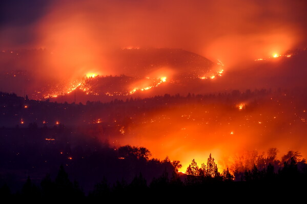 In this photo made with a long exposure, Bench Fire burns above the Pelton Reservoir in Jefferson County, Ore., July 25, 2026. (AP Photo/Noah Berger, File)