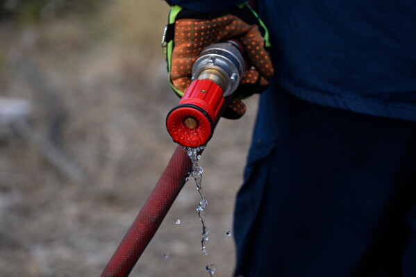 Water drips from a firefighter's hose nozzle during a wildfire near Porto Germeno, northwest of Athens, Greece, Sunday, Aug. 2, 2026. (AP Photo/Michael Varaklas)