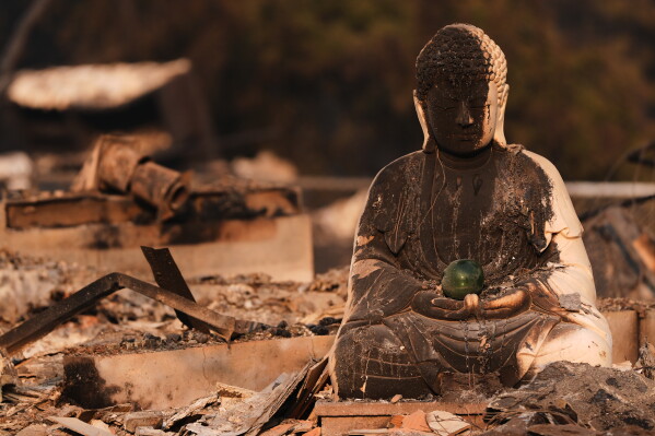 A Buddha statue is seen with fire damage amongst the rubble of a house burned after a wildfire hit the northern part of Spokane, Wash., Monday, Aug. 3, 2026. (AP Photo/Lindsey Wasson)