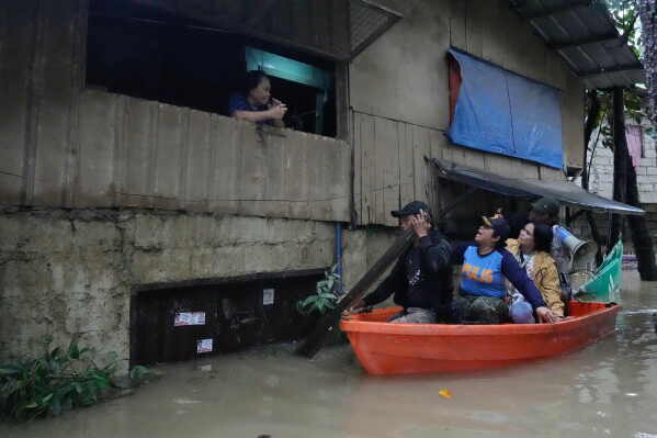 Police Lt. Col. Rowena Amata, second from left, and village officials, on boat, remind a resident to evacuate to higher grounds as floodwaters caused by heavy seasonal monsoon rains inundate a village at Bagong Silangan in Quezon city, Metro Manila, Philippines Monday, Aug. 10, 2026. (AP Photo/Aaron Favila) CORRECTION: Corrects typo in location to Silangan, instead of Silagan