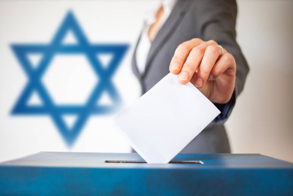 elections in Israel. Hand of a woman putting her vote in the ballot box. Waved Israel flag on background.