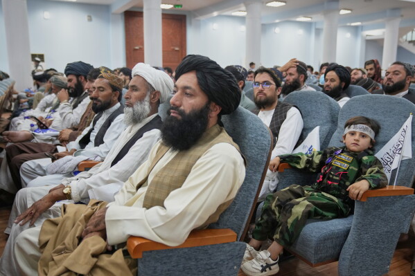 A boy sits among Taliban delegates from across the country during a meeting opening celebrations marking the fifth anniversary of the U.S. withdrawal and the Taliban's return to power, at Loya Jirga Hall in Kabul, Afghanistan, Saturday, Aug. 15, 2026. (AP Photo/Siddiqullah Alizai)