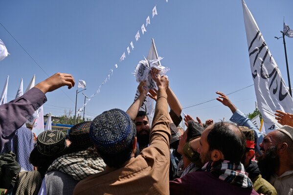 Taliban supporters reach for flags during celebrations marking the fifth anniversary of the U.S. withdrawal from Afghanistan and the Taliban's return to power, in Kabul, Afghanistan, Saturday, Aug. 15, 2026. (AP Photo/Nava Jamshidi)