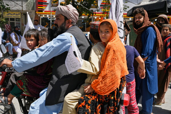 Children ride on a motorcycle carrying Taliban flags during celebrations marking the fifth anniversary of the U.S. withdrawal from Afghanistan and the Taliban's return to power, in Kabul, Afghanistan, Saturday, Aug. 15, 2026. (AP Photo/Nava Jamshidi)