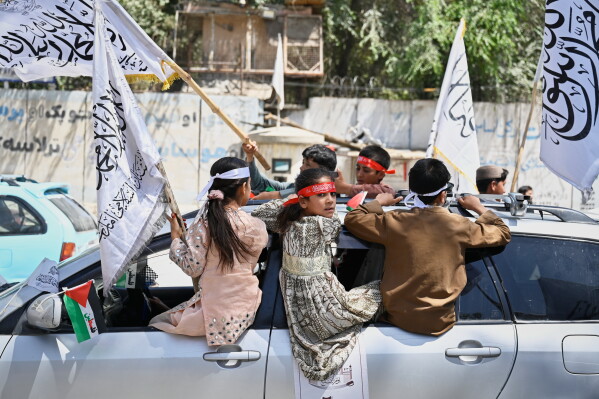 Children ride on a vehicle and wave Taliban flags during celebrations marking the fifth anniversary of the U.S. withdrawal from Afghanistan and the Taliban's return to power, in Kabul, Afghanistan, Saturday, Aug. 15, 2026. (AP Photo/Nava Jamshidi)