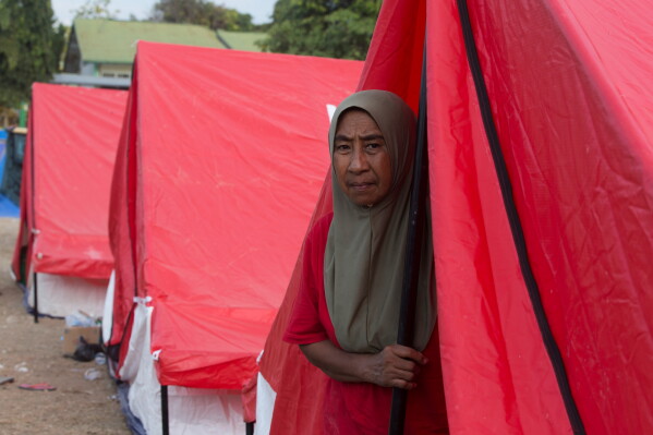 A woman looks out from at a temporary shelter for earthquake survivors in Reo, East Nusa Tenggara province, Indonesia, Monday, Aug. 17, 2026. (AP Photo/Firdia Lisnawati)