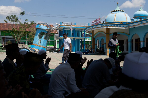 Muslims perform mid-day prayer outside an earthquake-damaged mosque in Reo, East Nusa Tenggara province, Indonesia, Monday, Aug. 17, 2026. (AP Photo/Firdia Lisnawati)