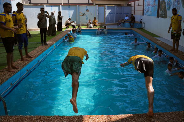 Amputee swimming trainees jump into a pool during a training session for Palestinian children who lost their legs after being injured during the war between Israel and Hamas, in Khan Younis, Gaza Strip, Wednesday, Aug. 19, 2026. (AP Photo/Abdel Kareem Hana)