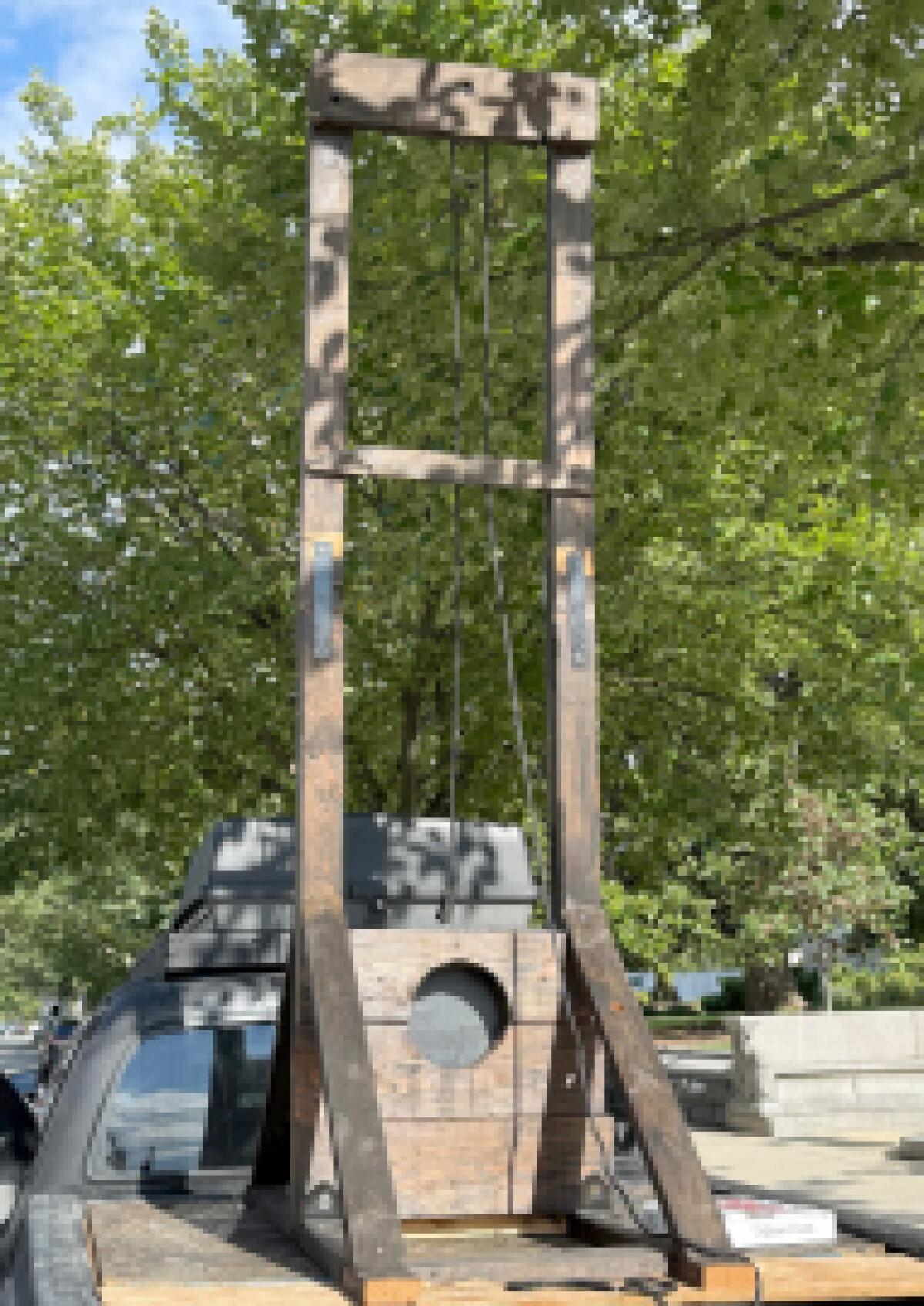 A guillotine rises from the bed of a pickup. 