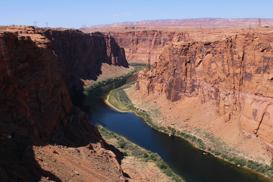 A wide river curves through a canyon of red rock cliffs