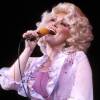 Dolly Parton sings into a microphone that she's holding.