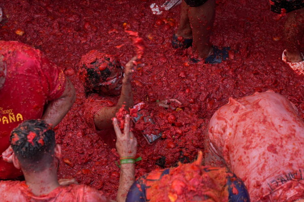 Revelers throw tomatoes at each other during the annual "Tomatina" tomato fight fiesta, in the village of Bunol near Valencia, Spain, Wednesday, Aug. 26, 2026. (AP Photo/Alberto Saiz)