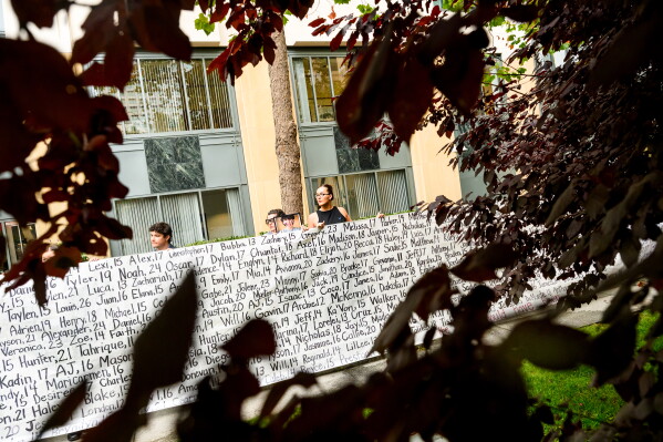Lennon Torres of Heat Initiative holds a banner with names of young people who advocates say died as a result of social media outside the Ronald V. Dellums Federal Building and U.S. Courthouse on Tuesday, Aug. 18, 2026, in Oakland, Calif. (AP Photo/Noah Berger)