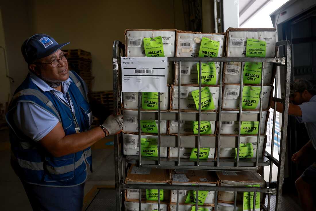 A U.S. Postal Service worker loads mail-in ballots onto a truck in 2022 in Miami.