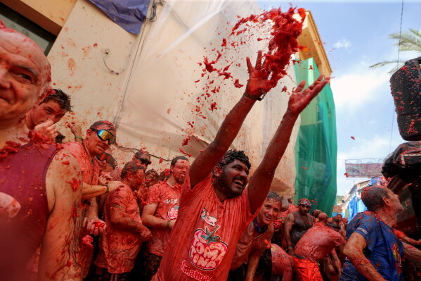 Revelers throw tomatoes at each other during the annual "Tomatina" tomato fight fiesta, in the village of Bunol near Valencia, Spain, Wednesday, Aug. 26, 2026. (AP Photo/Alberto Saiz)