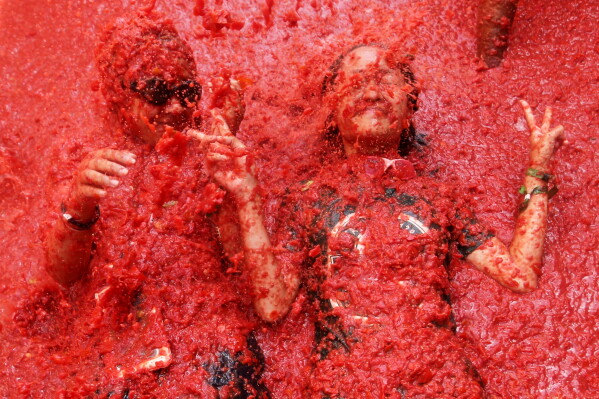 Revelers throw tomatoes at each other during the annual "Tomatina" tomato fight fiesta, in the village of Bunol near Valencia, Spain, Wednesday, Aug. 26, 2026. (AP Photo/Alberto Saiz)