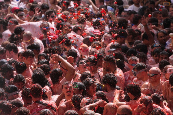 Revelers throw tomatoes at each other during the annual "Tomatina" tomato fight fiesta, in the village of Bunol near Valencia, Spain, Wednesday, Aug. 26, 2026. (AP Photo/Alberto Saiz)