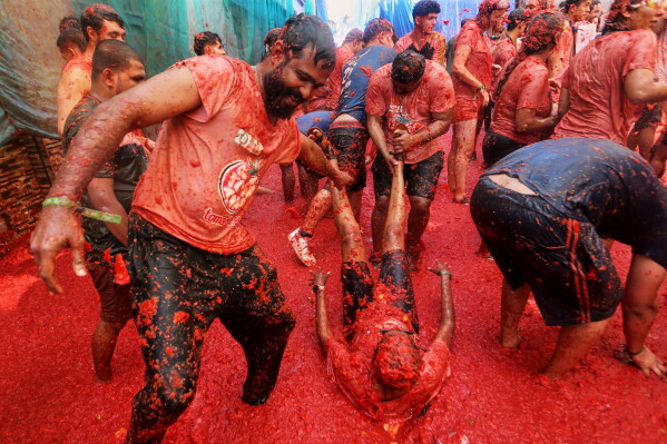 Revelers throw tomatoes at each other during the annual "Tomatina" tomato fight fiesta, in the village of Bunol near Valencia, Spain, Wednesday, Aug. 26, 2026. (AP Photo/Alberto Saiz)