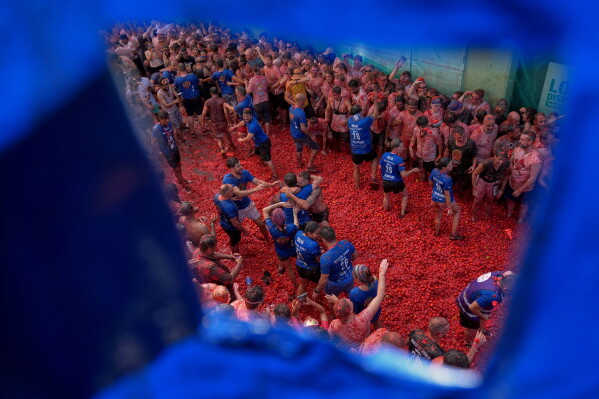 Revelers throw tomatoes at each other during the annual "Tomatina" tomato fight fiesta, in the village of Bunol near Valencia, Spain, Wednesday, Aug. 26, 2026. (AP Photo/Alberto Saiz)