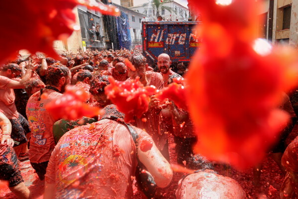 Revelers throw tomatoes at each other during the annual "Tomatina" tomato fight fiesta, in the village of Bunol near Valencia, Spain, Wednesday, Aug. 26, 2026. (AP Photo/Alberto Saiz)