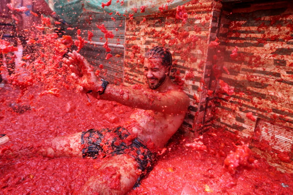 A reveler takes part in the annual "Tomatina" tomato fight fiesta, in the village of Bunol near Valencia, Spain, Wednesday, Aug. 26, 2026. (AP Photo/Alberto Saiz)