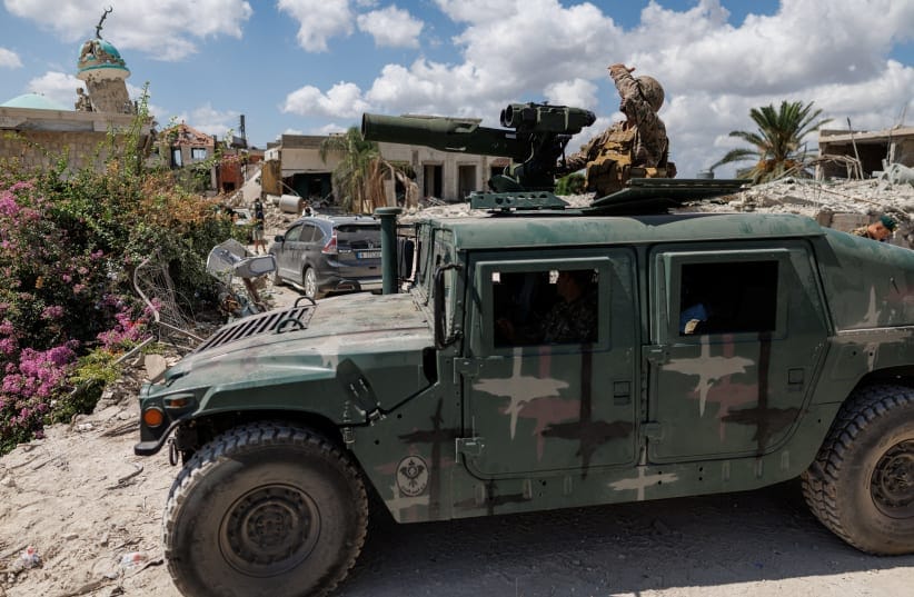 A Lebanese army officer looks up at an Israeli drone while standing on an armoured vehicle in Zawtar al-Gharbiyeh, a village in southern Lebanon, as Lebanese soldiers deploy in one of three pilot zones following the withdrawal of Israeli forces under a US-brokered plan, July 26, 2026. 