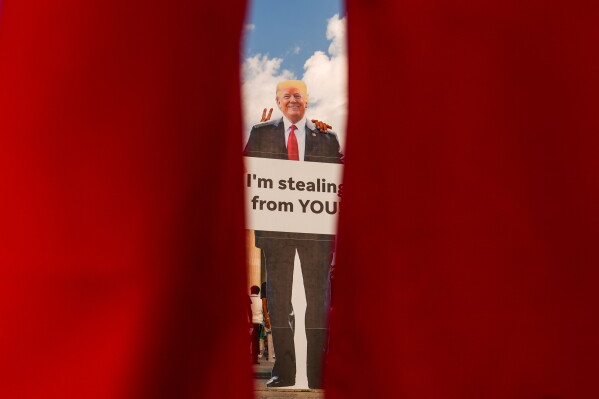Demonstrators take photos with a cardboard cut out of President Donald Trump near the Lincoln Memorial before the March on Washington, Friday, Aug. 28, 2026, in Washington. (AP Photo/Julia Demaree Nikhinson)
