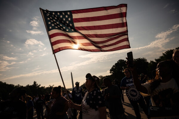 A demonstrator holds an American flag near the Lincoln Memorial before the March on Washington, Friday, Aug. 28, 2026, in Washington. (AP Photo/Julia Demaree Nikhinson)