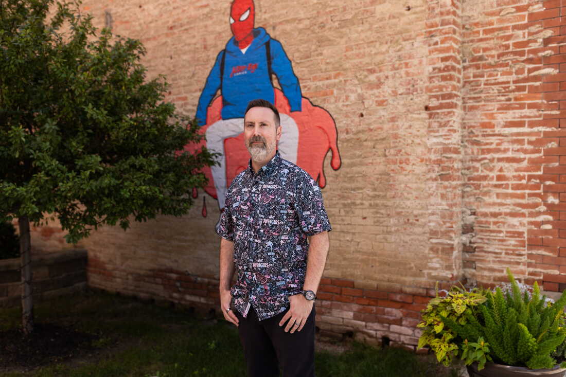 Bowker stands outside the store in front of a mural of Spiderman.