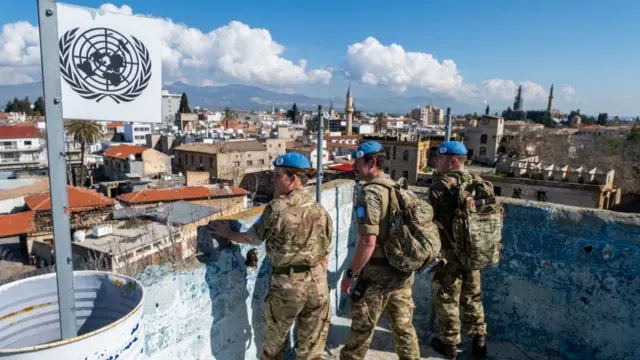 Members of the United Nations Peacekeeping Force in Cyprus climb up on a rooftop of an abandoned building while patrolling along a buffer zone