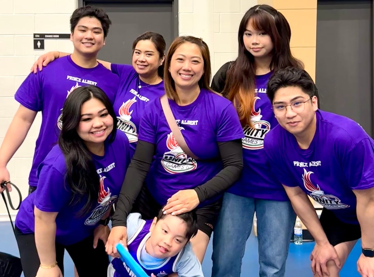 A family in matching purple t-shirts poses for a photo.