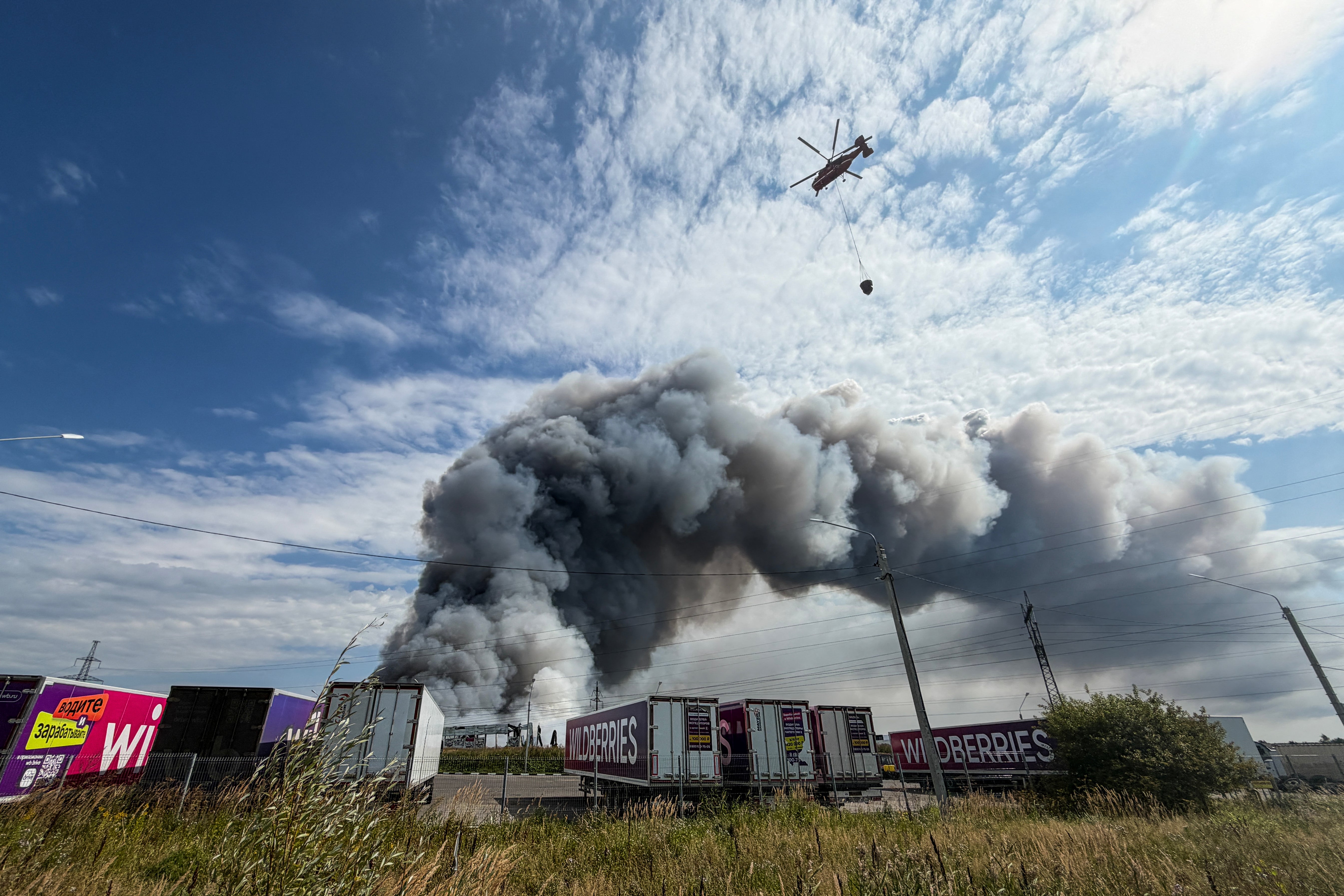 A firefighting helicopter prepares to drop a load of water during a fire at Russian e-commerce firm Wildberries' logistics complex near the town of Podolsk, outside Moscow on August 16, 2026.
