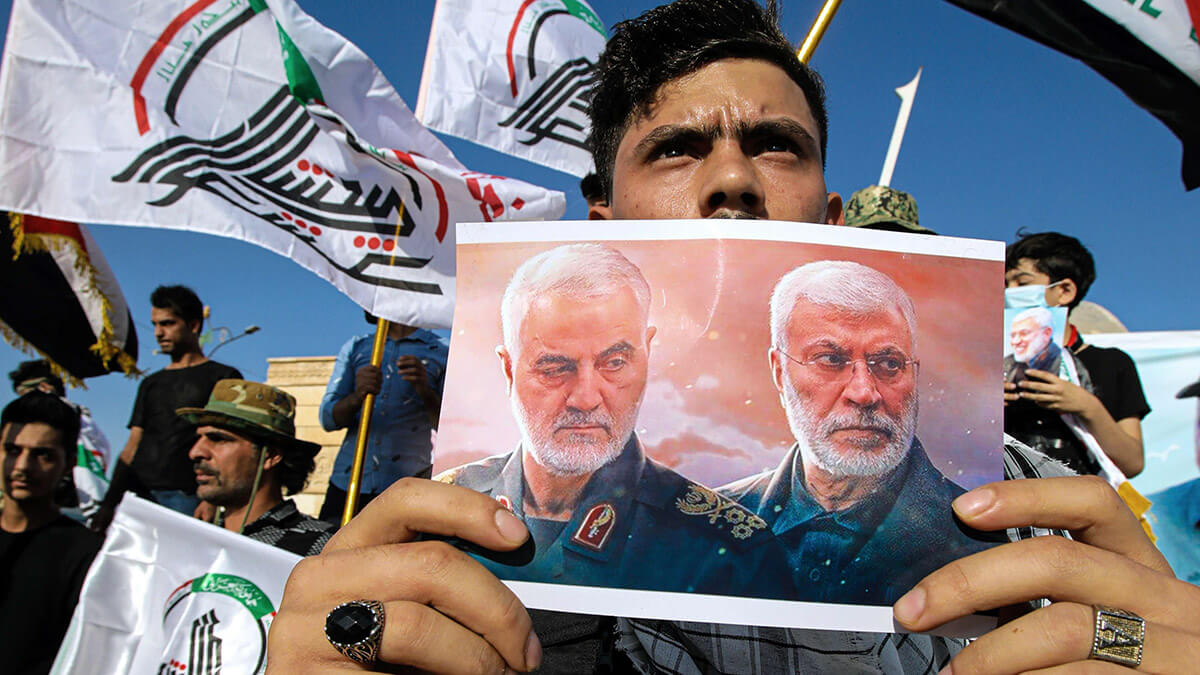A supporter of an Iran-backed militia holds a poster of Iranian General Qasem Soleimani and Deputy Commander Abu Mahdi al-Muhandis during a protest by pro-Iranian militiamen and their supporters to condemn remarks by a senior Kurdish government official - AP/ NABIL AL-JURANI