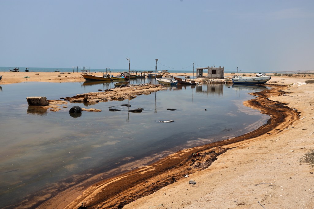 Oil residue along the shore near fishing boats on Qeshm Island, Iran.