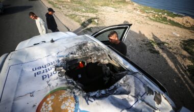 Palestinians are standing next to a vehicle in Deir Al-Balah, in the central Gaza Strip, on April 2, 2024, where employees from the World Central Kitchen (WCK), including foreigners, were killed in an Israeli airstrike.
