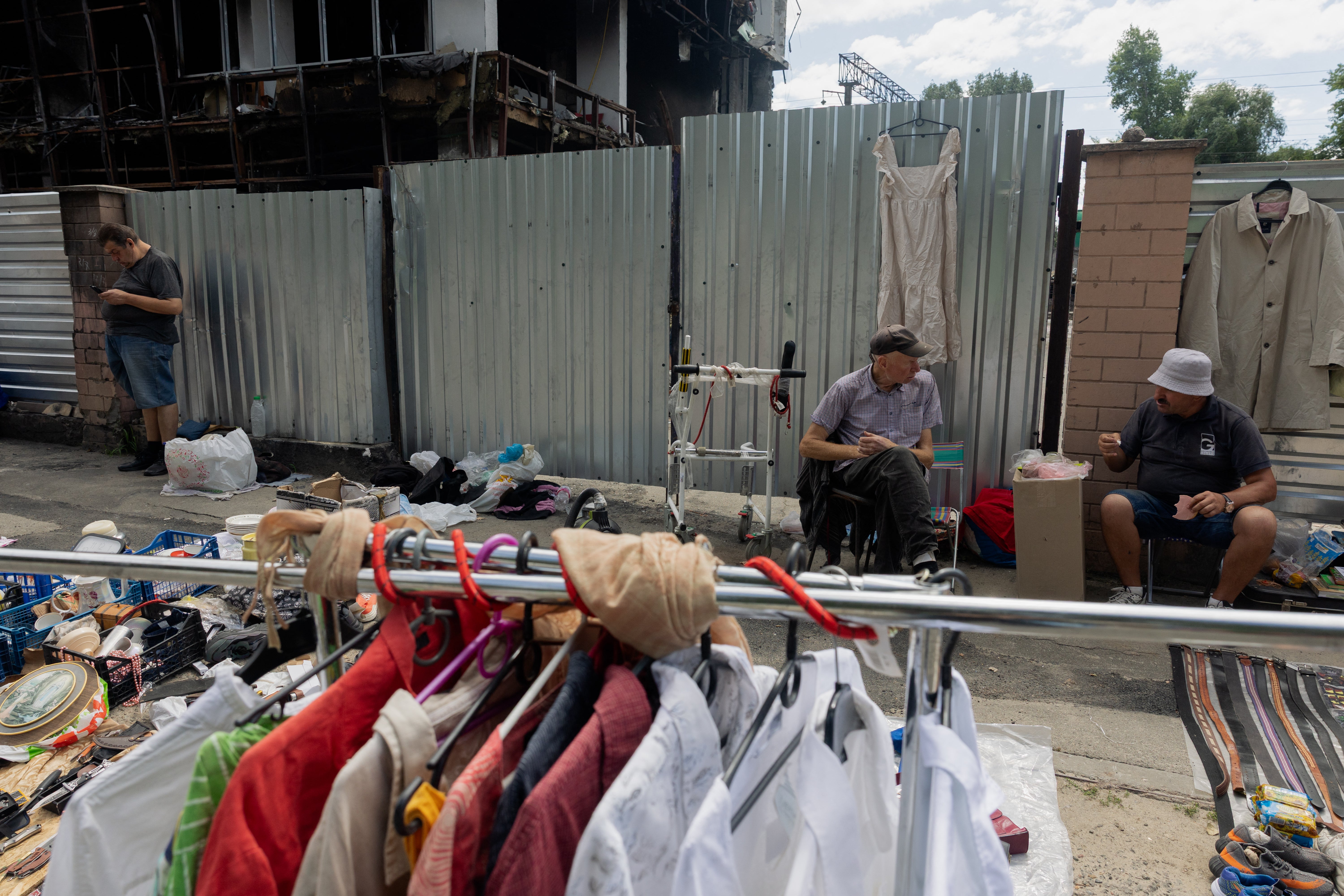 Vendors sit in front of their stalls at a damaged street market following strikes in Petrivka, one of Kyiv's neighborhoods