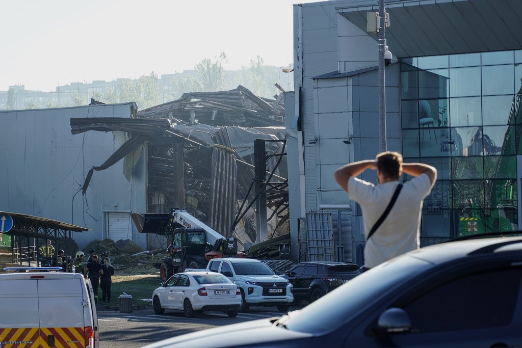 A man looking at a heavily damaged shopping center after a Russian drone attack.